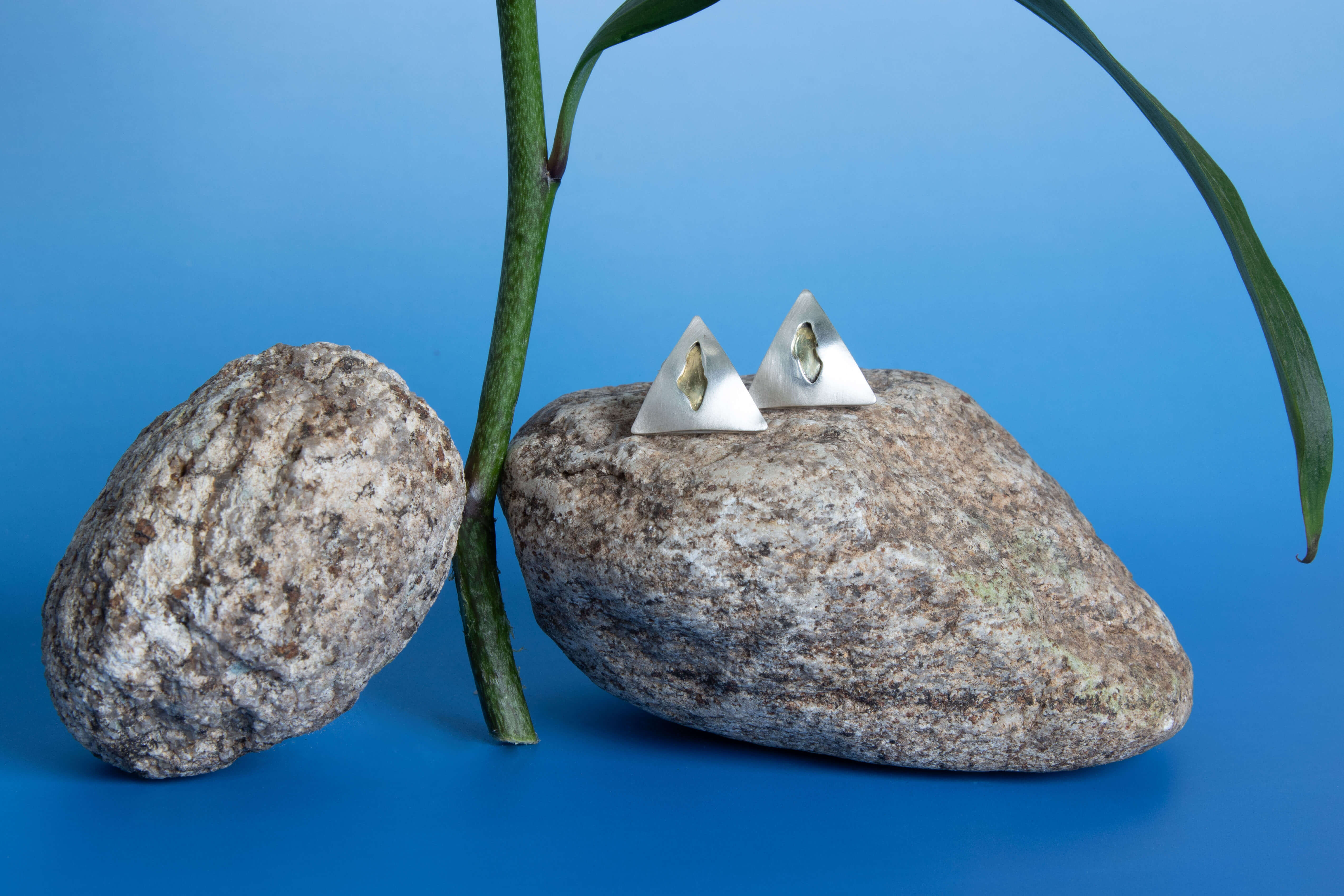 Brincos triângulo prata sobre pedras e caule azul